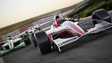 Red race car close up front view on a track leading the pack with motion Blur